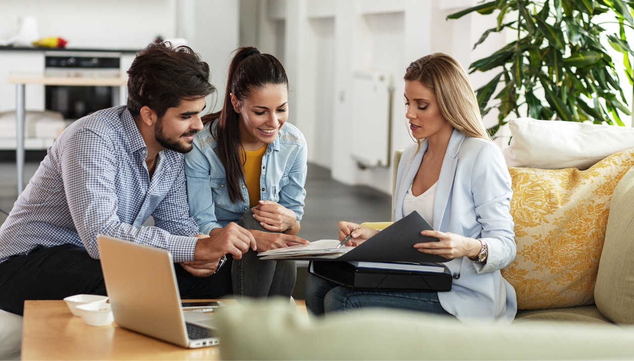 An agent advising a young couple in their home.